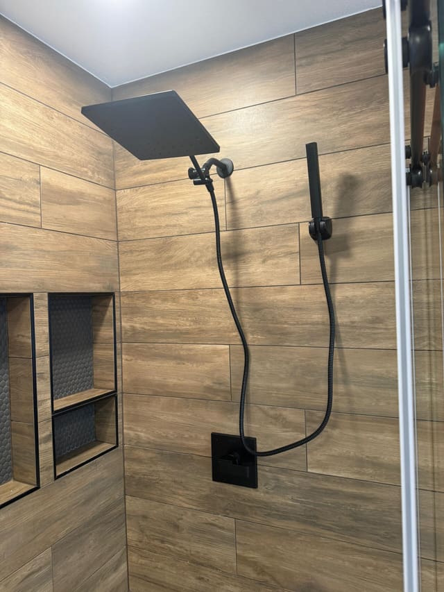 Rain head above and handheld shower on a slide bar, beside two tiled recessed niches