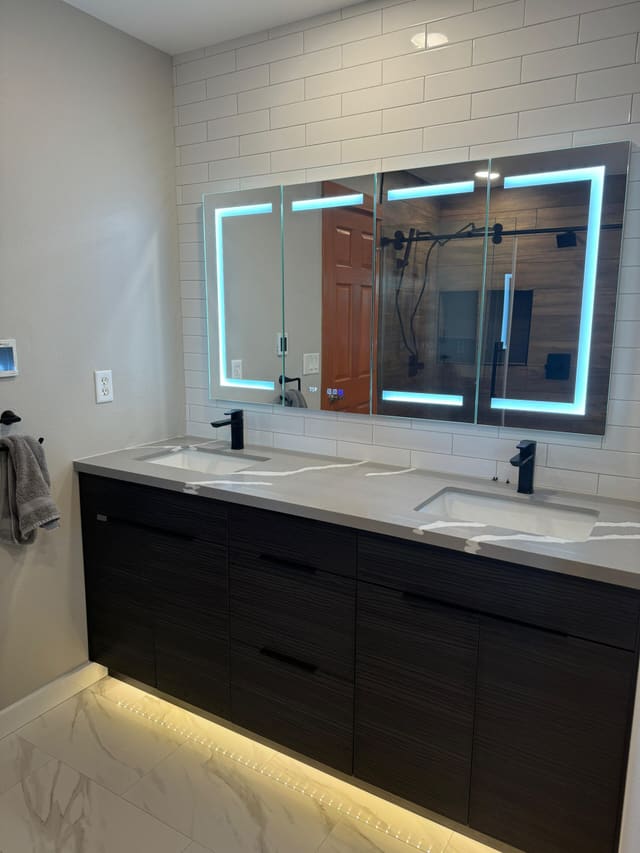 Double vanity with two sinks, backlit LED mirrors, dark cabinets and under-cabinet lighting